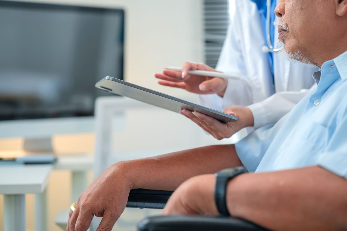 Physician reviewing health information on a tablet with an adult patient